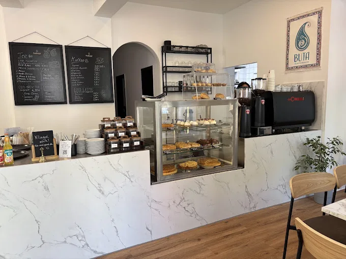 Theke mit Kuchenvitrine und Kaffeemaschine im BUTA CAFÉ